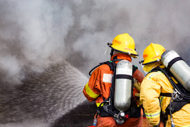 istock two firefighters water spray by high pressure nozzle to fire surround with smoke and copy space 869571014