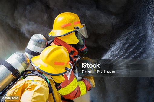 istock two firefighters water spray by high pressure nozzle to fire surround with smoke and copy space 869571218