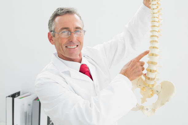 istock Smiling doctor holding skeleton model in office 869573842