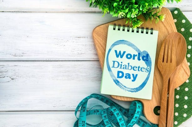 istock Notepad with World Diabetes Day text on chopping board with wooden fork and spoon and the measuring tape on the white table , Diabetes world day on 14 November encourage awareness campaign background concept 869576642