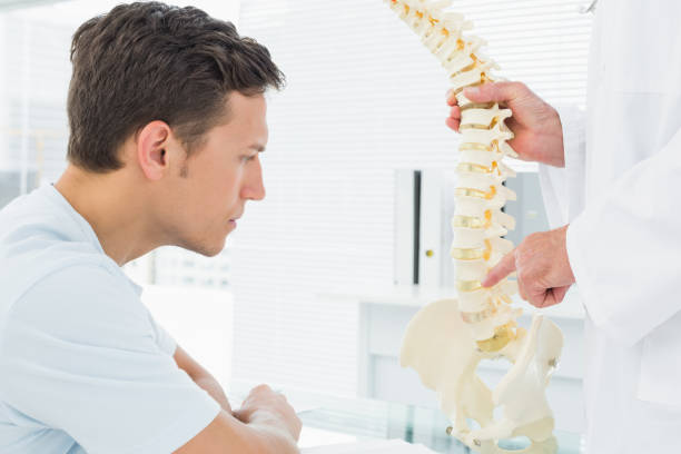 istock Doctor explaining the spine to a patient in office 869577068