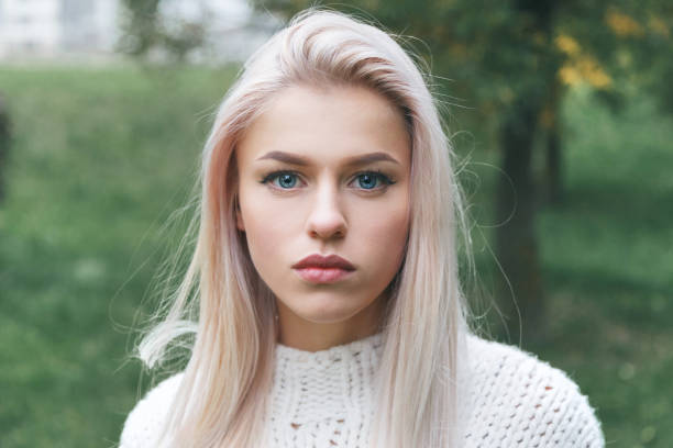 Portrait of a beautiful serious blonde girl in a white knitted sweater. Portrait of a beautiful serious blonde girl in a white knitted sweater victoria beckham stock pictures, royalty-free photos & images