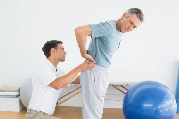 istock Therapist massaging mans lower back in gym hospital 869578134