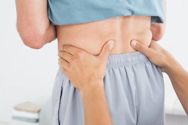 istock Hands massaging mans lower back in gym hospital 869578140