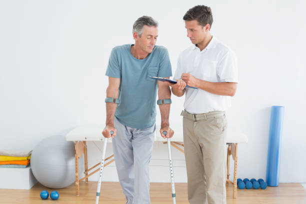 istock Therapist discussing reports with disabled patient in gym hospital 869578224