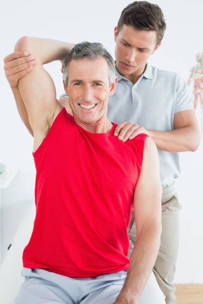 istock Physiotherapist stretching a smiling mature mans arm 869581026