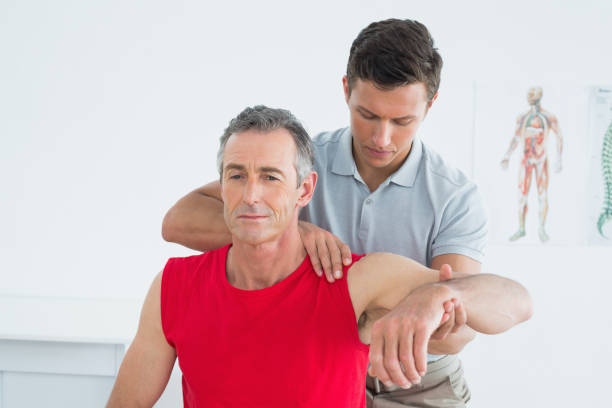 istock Male physiotherapist stretching a mature mans arm 869581066