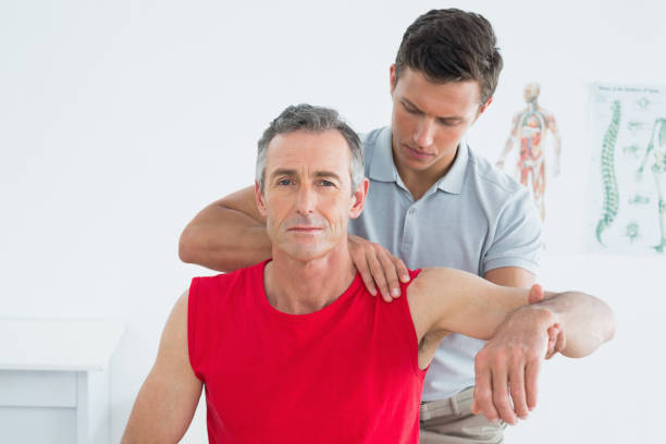 istock Male physiotherapist stretching a mature mans arm 869581072