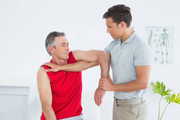 istock Male physiotherapist stretching a mature mans arm 869581100