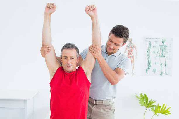 istock Male physiotherapist stretching a mature mans arms 869581130