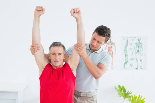 istock Physiotherapist stretching a mature mans arms 869581134