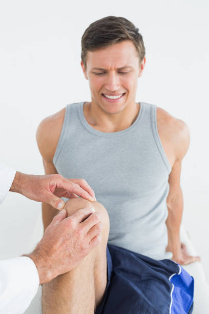 istock Displeased young man getting his knee examined 869584396