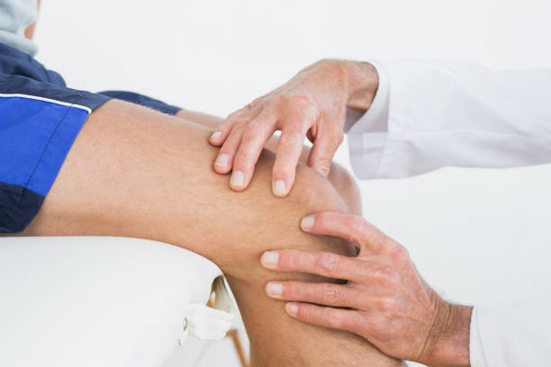 istock Closeup of hands examining patients knee 869584412
