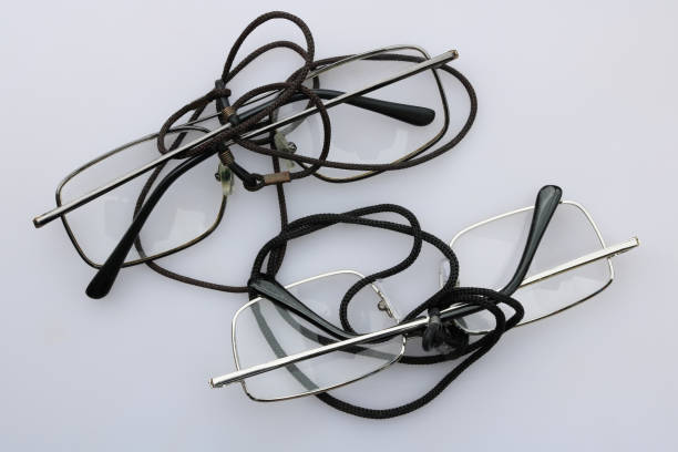 My grandfather's old glasses are on a white table. Simple steel frame of plastic glasses and neck straps