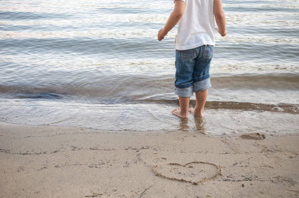istock Little girl standing on lake shore sand 869591396