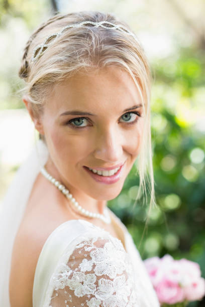 istock Blonde bride in a veil smiling to camera 869592012