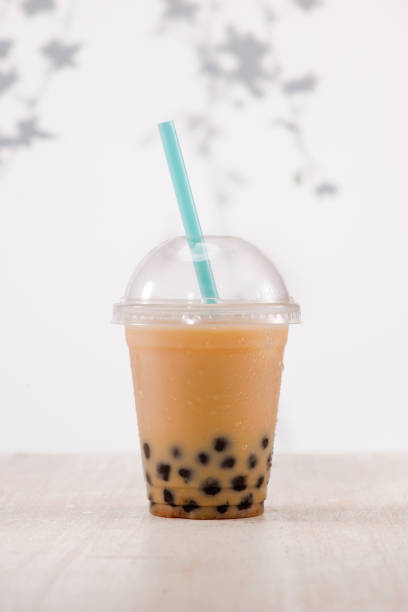 istock Light brown creamy bubble tea and black tapioca pearls  in plastic cups on table. 869594774
