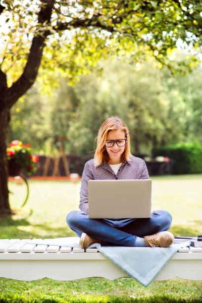 屋外の勉強ノート パソコンを持つ若い女性。 - vertical single flower women teenager ストックフォトと画像