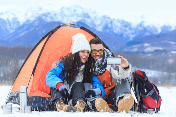 istock Couple backpackers taking selfie in front of a tent 869599300