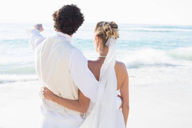 istock Newlyweds standing by the sea with husband pointing 869602788
