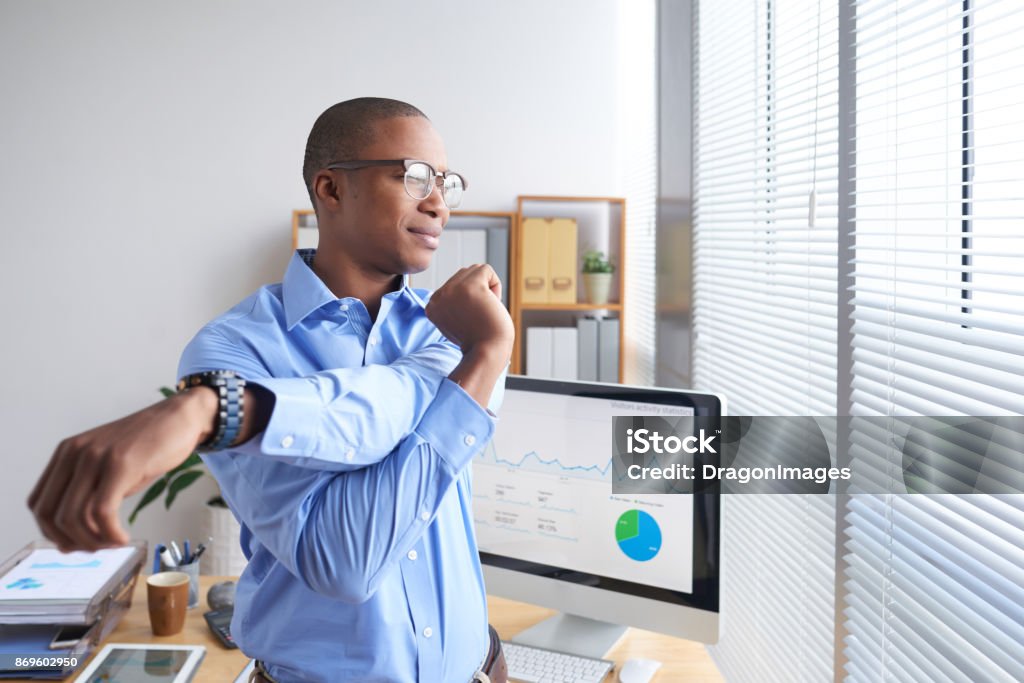 Stretching man Smiling Black business executive stretching his arms during little break Stretching Stock Photo