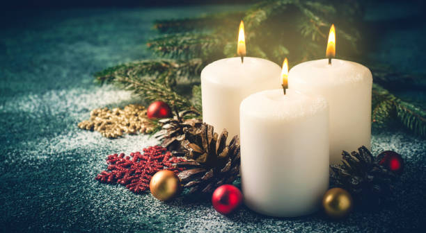 istock Three Christmas burning candles and decorations on dark turquoise background 869606734