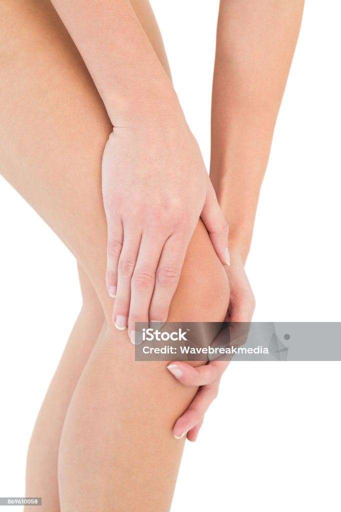 Closeup mid section of a woman with knee pain Closeup mid section of a young woman with knee pain over white background Pain Stock Photo