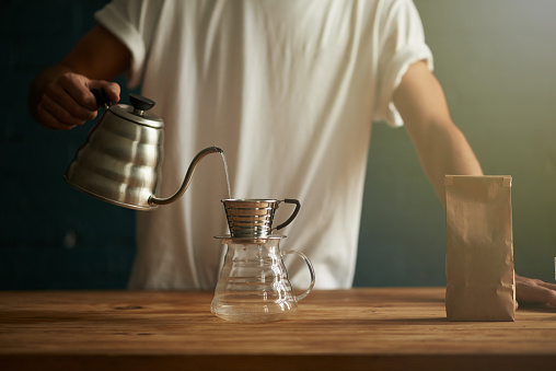 Cropped shot of a man preparing a pot of freshly brewed coffee