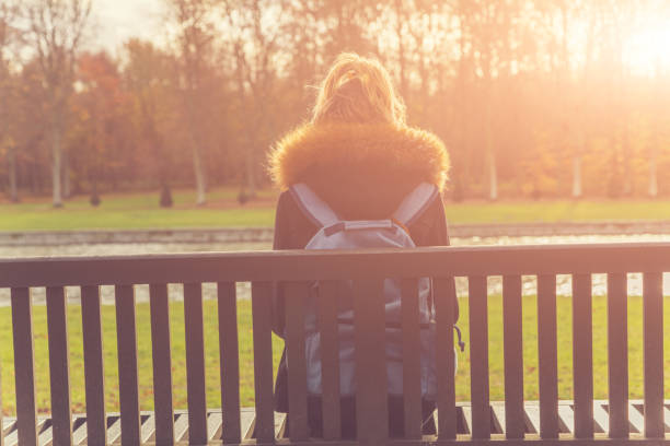istock Lonesome girl sitting on a park bench. 869613932