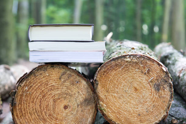 istock Books lying on felled trees,  Save the trees - read e-books 869614366