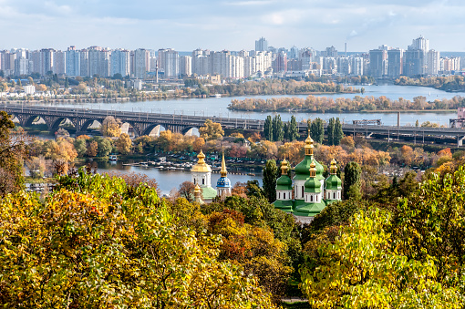 Panoramic view of Kiev city and George Cathedral of the Vydubychi Monastery among the trees of the park in autumn. Kiev, Ukraine.