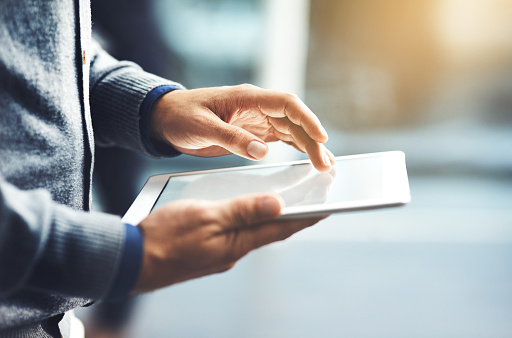 Closeup shot of an unrecognisable businessman using a digital tablet in an office