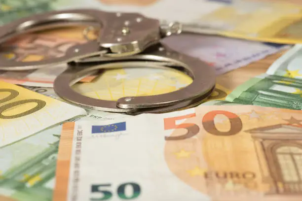 Photo of Handcuffs and Euro banknotes