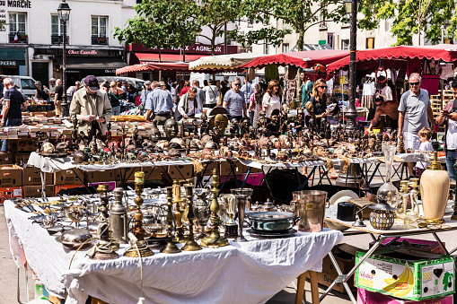 Paris, France - Jule 09, 2017: People choosing rare and used books, wooden masks and figures of African culture at the historic flea Aligre Market (Marche d'Aligre) in the Bastille district.