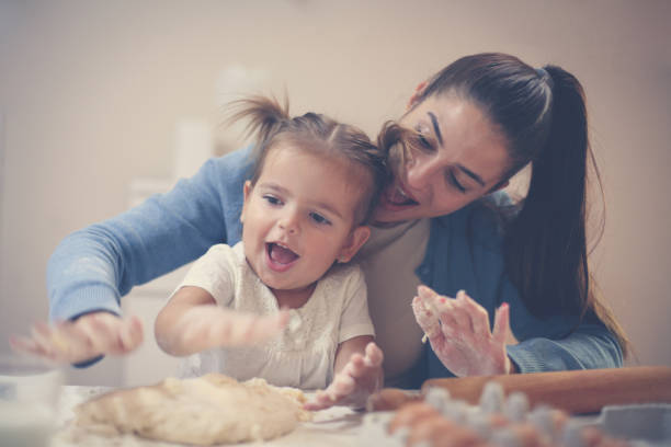 istock Smiley mother and daughter at home making dough for cookie and playing. 869619742