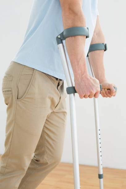 istock Side view mid section of a man with crutches 869626796