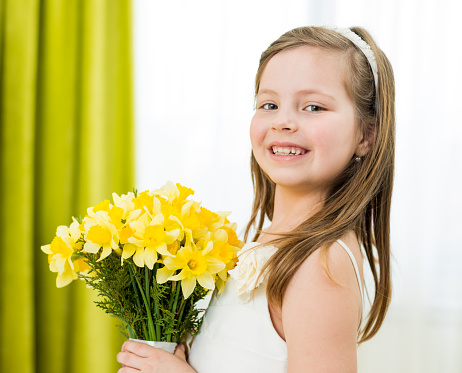 Portrait of young girl holding bouquet of daffodils
