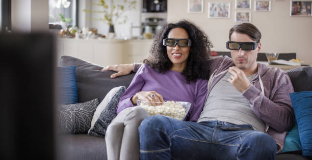 istock Young couple watching TV with 3D glasses 869630750