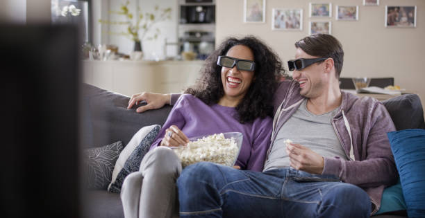 Young couple watching TV with 3D glasses