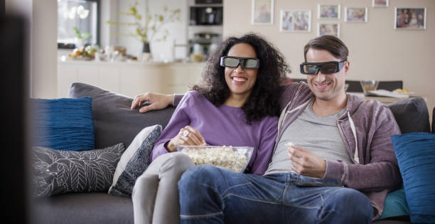 istock Young couple watching TV with 3D glasses 869630826