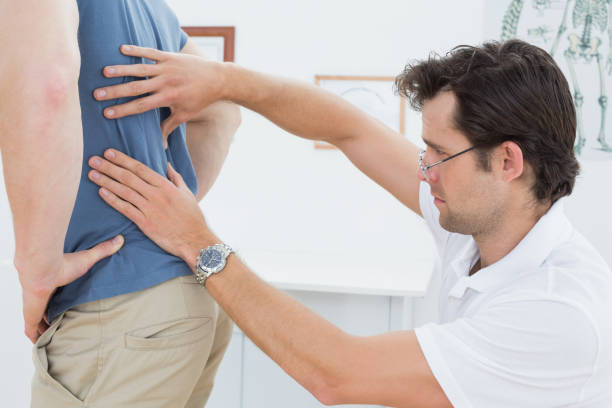 istock Side view of a male physiotherapist examining mans back 869634064