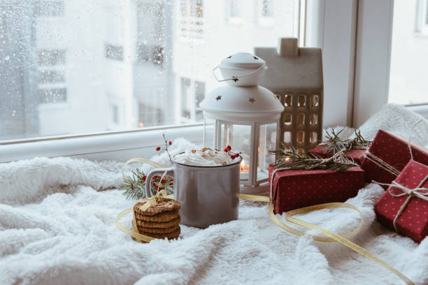 Christmas decoration with presents, mug with whipped cream in it and candlelight