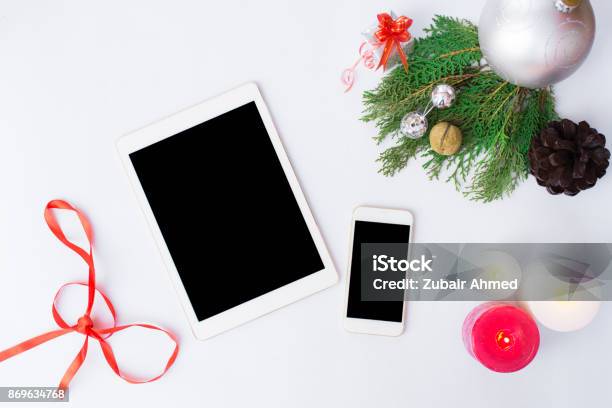 Tablet Smartphone Cell Phone With Christmas Decoration Silver Ribbon Branch Of Pane Silver Snowflake Snow Cone New Year Stock Photo - Download Image Now