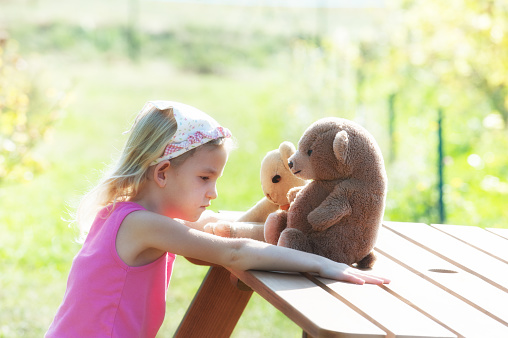 Little girl shares her worries with two teddy bears
