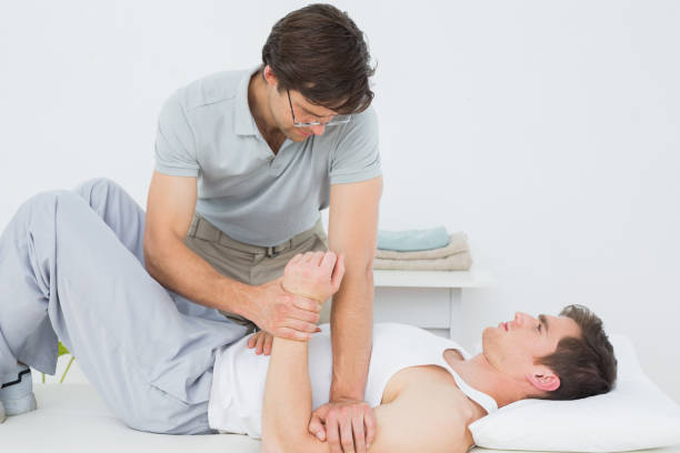 istock Male physiotherapist examining a young mans hand 869645340
