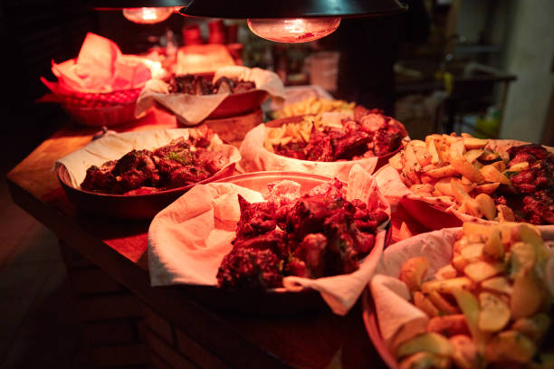 A full table with various dishes in a restaurant or a cafe under the red light of a lamp