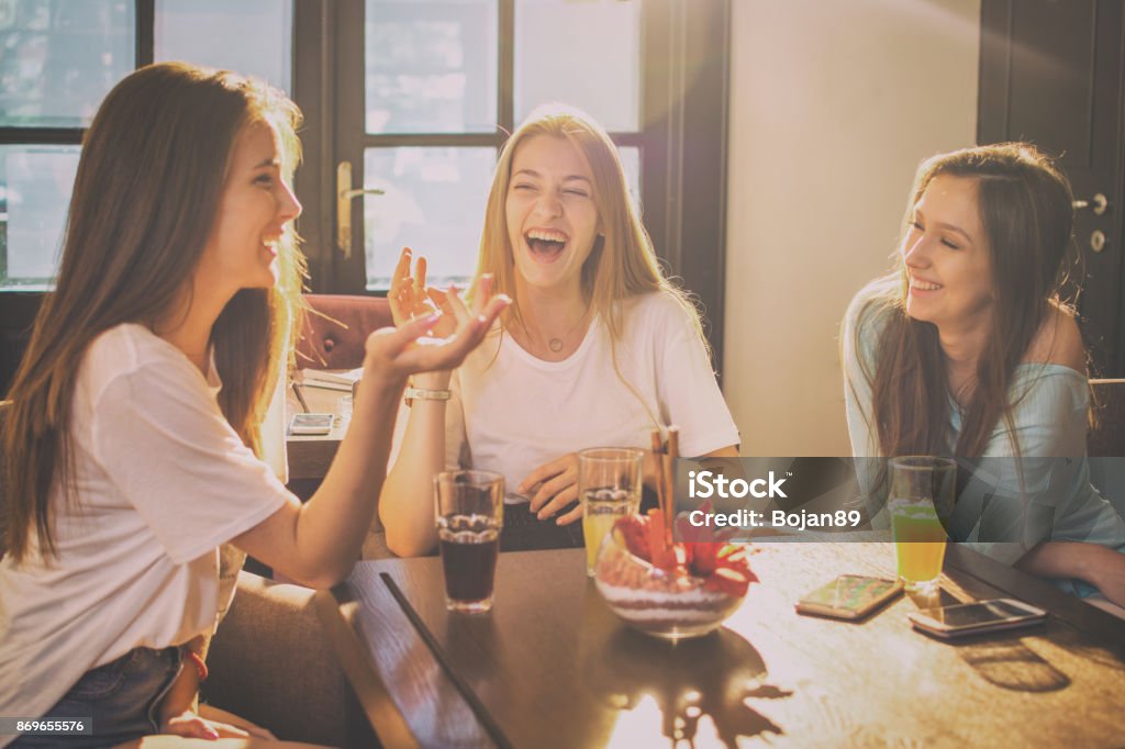 Happy teenage girls talking and laughing in a cafe. Teenage Girls Stock Photo