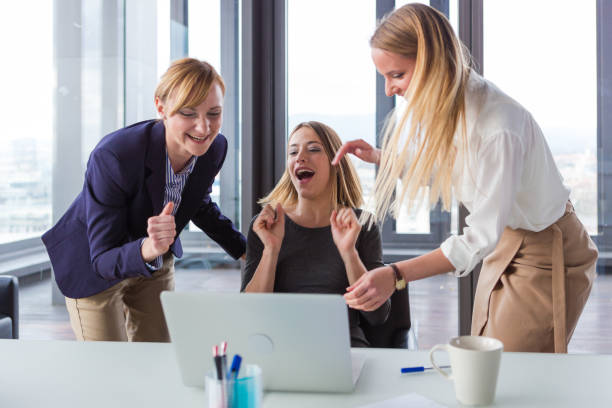istock Three business women in modern office celebrating good project results. 869657994
