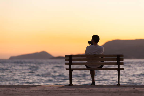 istock Lonely Man Sitting Watching the Sunset 869661840