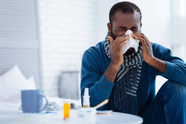 istock Pleasant young man sitting and sneezing 869665678